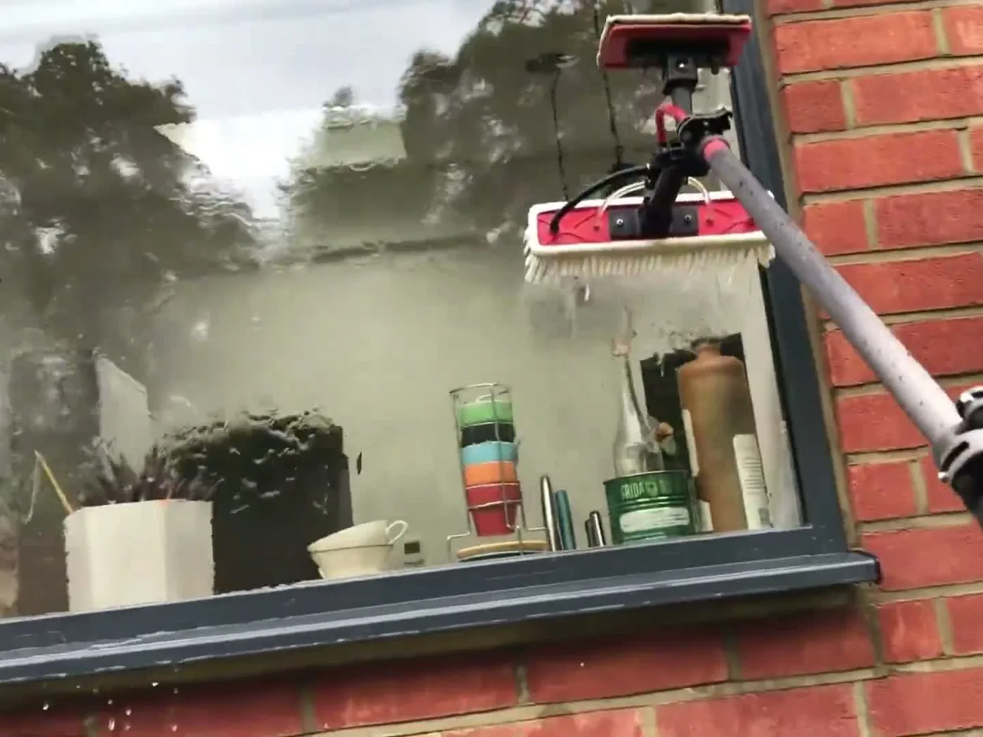 A water-fed pole cleaning a large ground-floor window from ground level