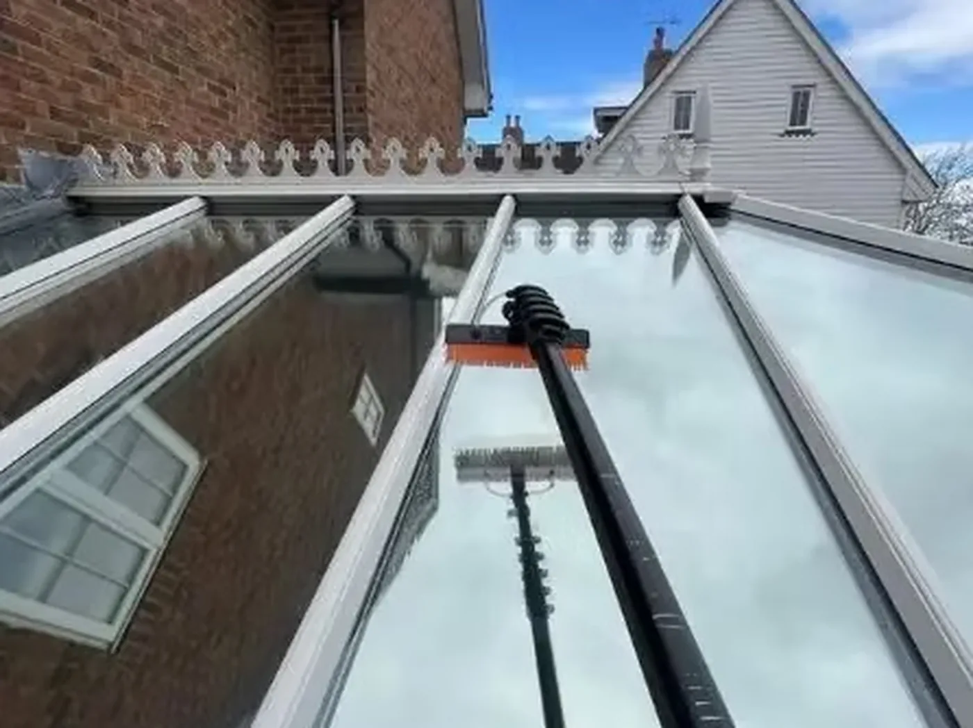 A conservatory glass roof being cleaned with a pole from below