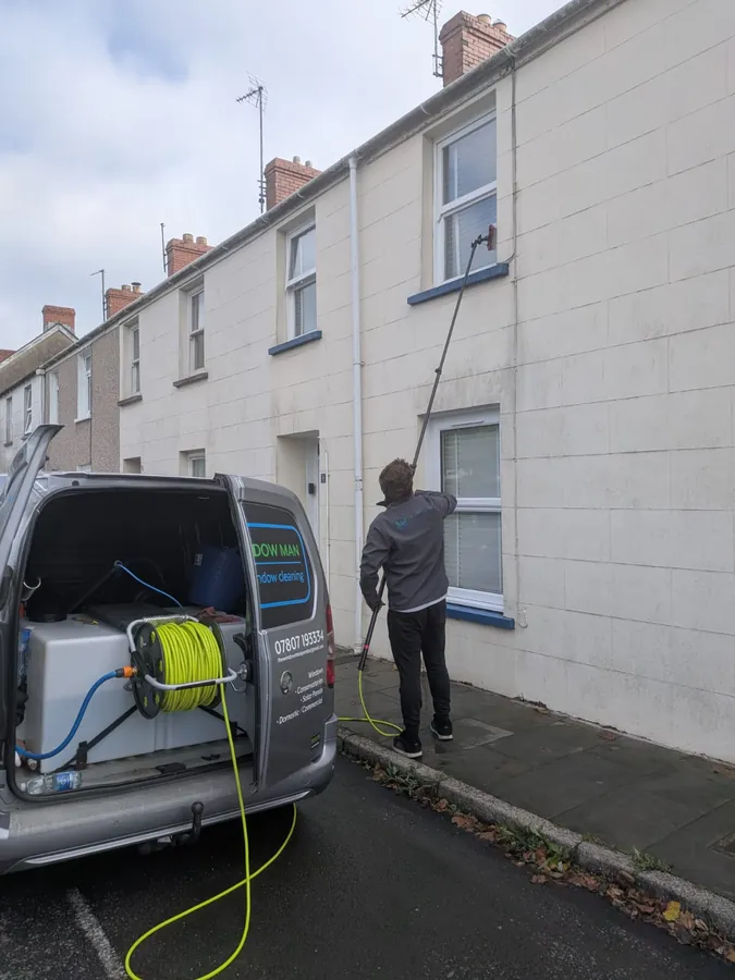 Cleaning upstairs windows on a terrace house with a water-fed pole
